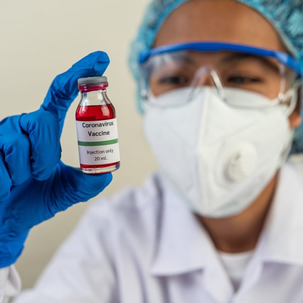 Scientists wearing masks and gloves, carrying vials with vaccine Scientists wearing masks and gloves, carrying vials with vaccines to protect Covid-19